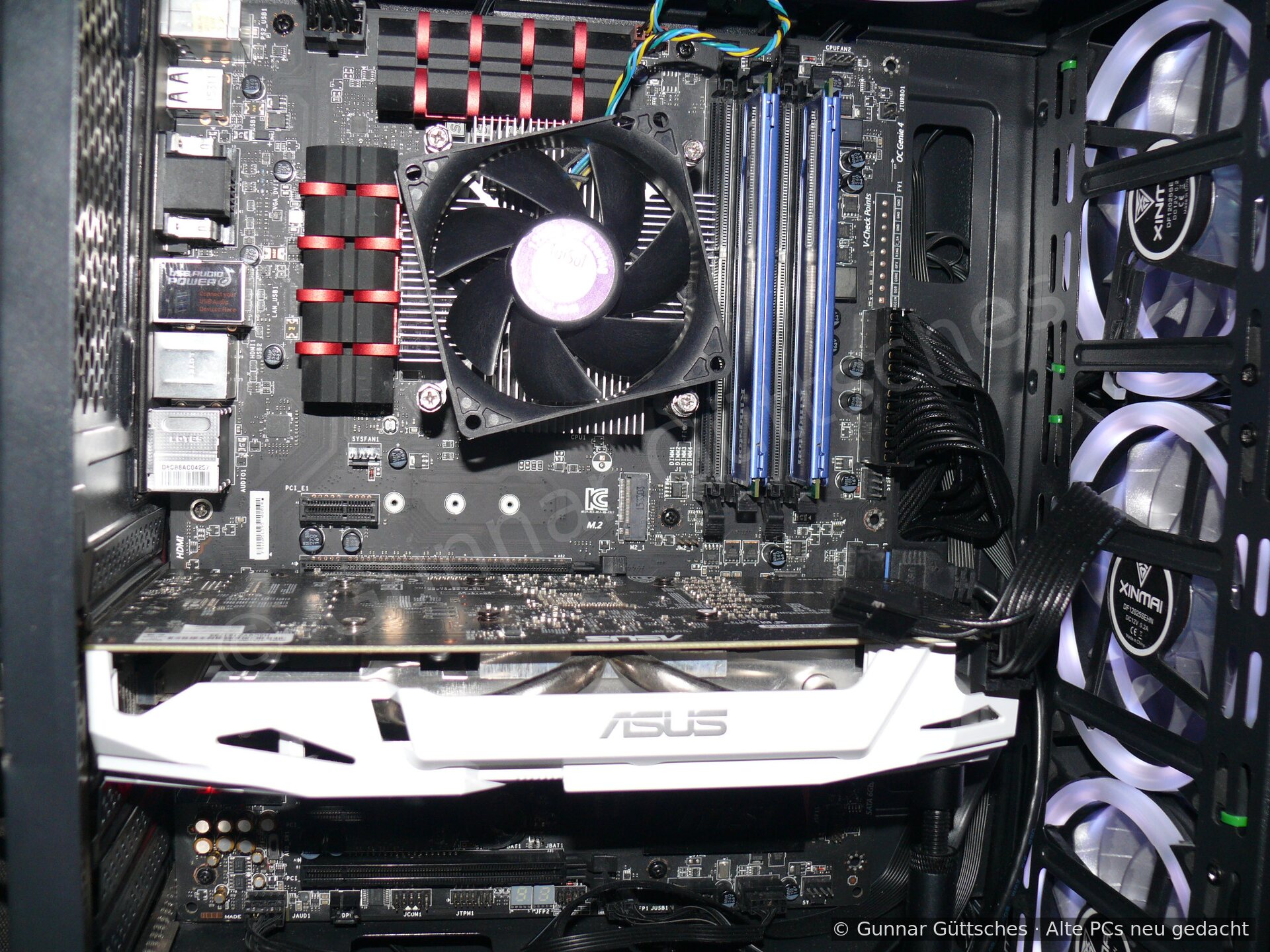 Innenraum mit Mainboard, Prozessorkühler, Arbeitsspeicher und weißer ASUS-Grafikkarte